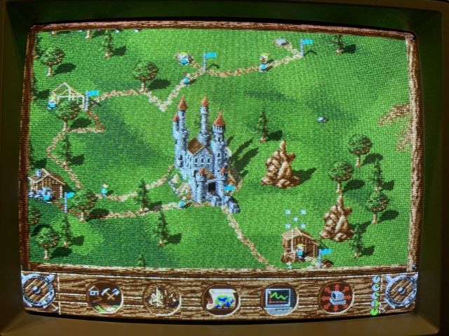 A pixelated CRT screen showing the settlers map with the castle and a few buildings.
