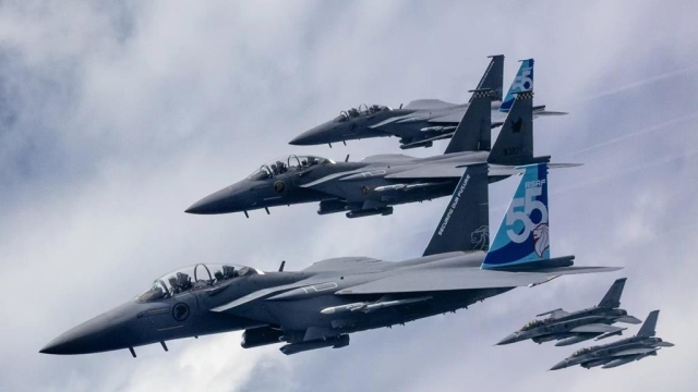 Three Singaporean F15 Eagle fighters are flanked by two F16 fighter jets.