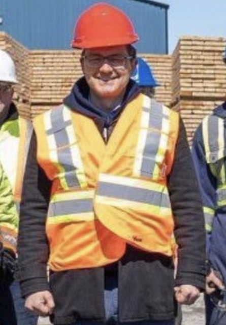 Poilievre wearing a badly fitted reflective work vest and a red hard hat perched on his head.

Credit @rodKahx