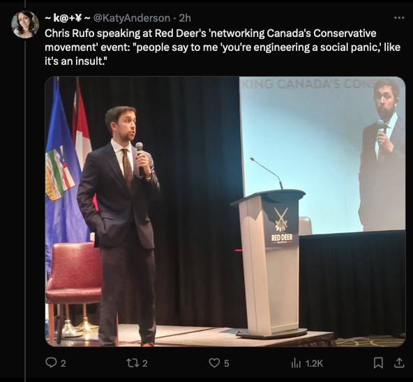 A tweet from @KatyAnderson with a photo of Chris Rufo on stage wearing a dark suit and brown tie (very demure, very mindful) holding a microphone, with a nearby podium that says "Red Deer." The tweet reads: "Chris Rufo speaking at Red Deer's 'networking Canada's Conservative movement event: "people say to me 'you're engineering a social panic," like it's an insult."