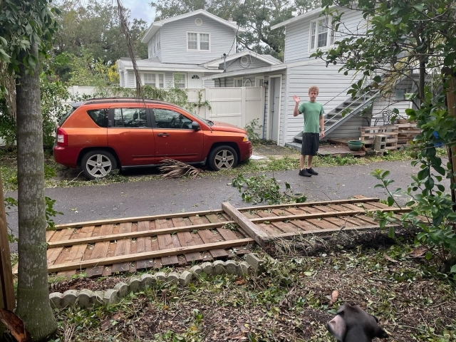 A neighbor waves as his wife takes a photo of a section of fencing that blew over into the alleyway behind our house.