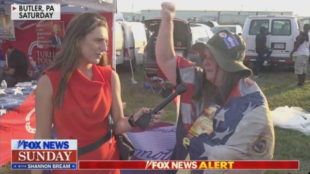 A Trump supporter being interviewed after the attempted assassination in Butler, PA, draped in an American flag, wearing an a floppy "Gilligan" hat.