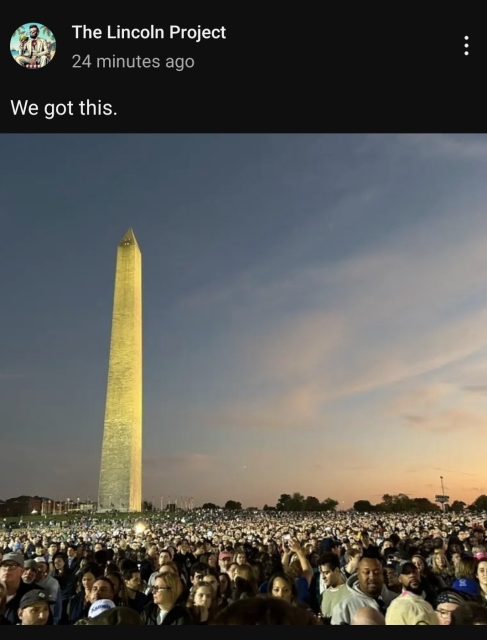 A crowd, estimated at 50-75 thousand people, gathers at sunset on the Ellipse in Washington, DC. to hear Kamala Harris speak. Washington Monument obelisk rises on the left above the crowd.
Skies are blue with hazy pink clouds above the treeline in the distance.