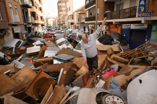 Original caption: Un hombre camina sobre la basura y escombros arrastrados por las inundaciones, este miércoles en Sedaví (Valencia).

A man walks over a mass of debris from the flood in Sedavi. 