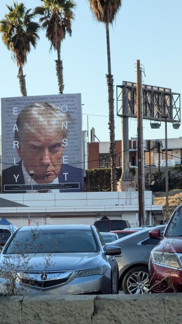 Photo taken in Los Angeles near the 110 and the 10. Photo is billboard of Trump's mugshot, perhaps 15' x 15' (I'm horrible with that kind of estimate) with the words "early onset" easily seen, other text overlayed on the image I can't make out.