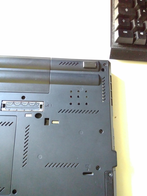 The back of a T420 ThinkPad laptop with 9 small holes drilled into it, where the fan intake is.