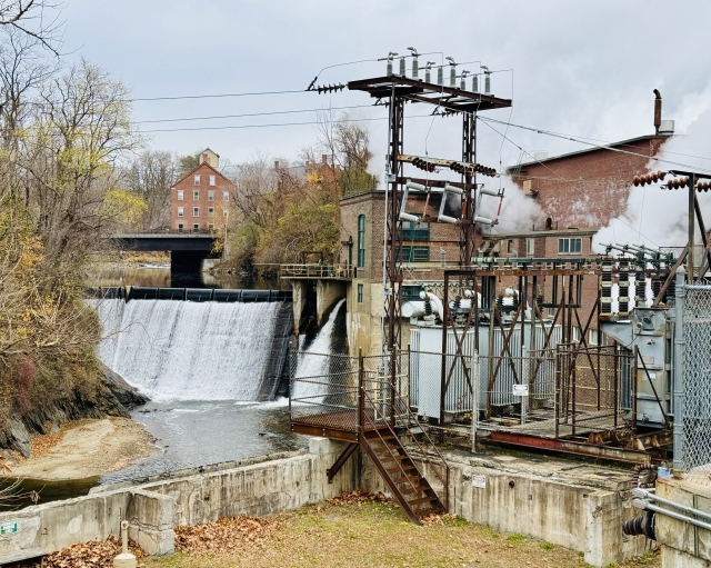 in the old mill section of town, a water fall, power transformers, and steam billowing out of various big brick buildings