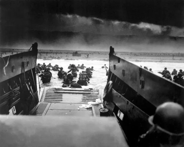 American soldiers leave the ramp of a Coast Guard landing boat under heavy Nazi machine gun fire (Normandy, June 6, 1944; Photo: Reuters)