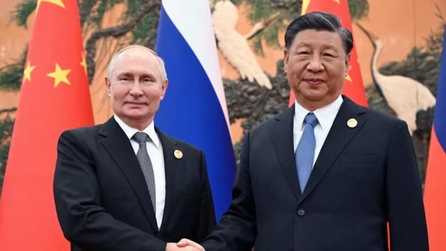 Putin and Xi shaking hands and smiling