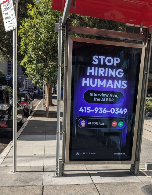 An ad on a muni stop saying "Stop hiring humans."