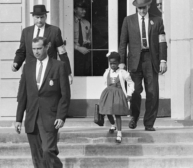 Ruby Bridges walking down the steps of the school, surrounded by federal marshalls. She is a six year old Black girl in a wide-skirted dress, carrying her schoolbag. They are tall white men in suits and hats.