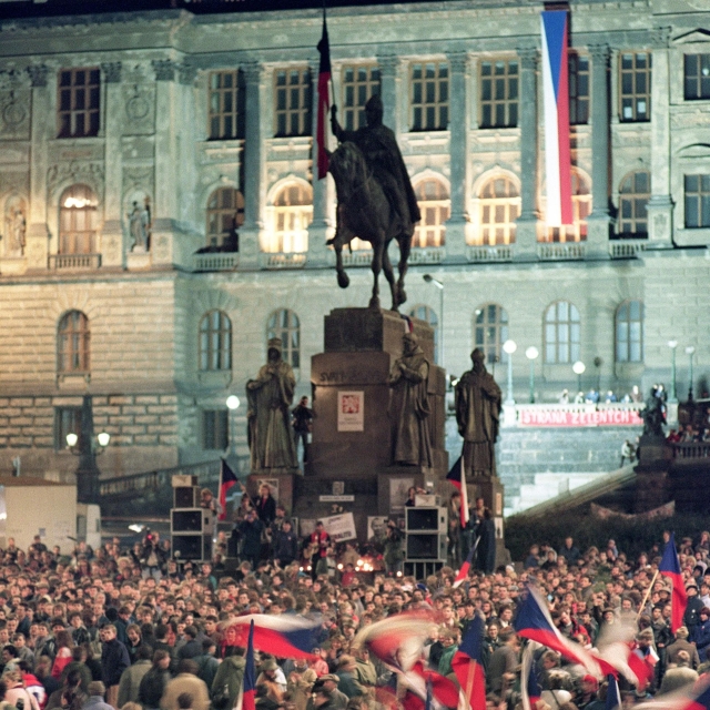 Students waving country flags, during a protest rally in front of mounted statue of St. Wenceslas and National Museum at Wenceslas Square in Prague.  Many flags are waving, and a little stage is set before the statue.  