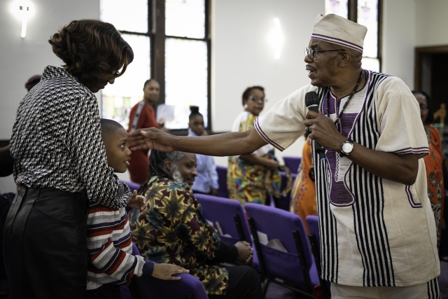 Reverend Robert McCathern approaches Tayler Armstrong, 9, and his grandmother Patricia Stewart-Burton while preaching during a Sunday service at Joy Tabernacle Church in Flint, Michigan.