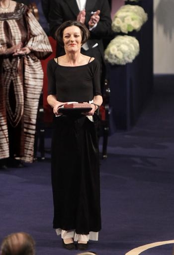 Herta Müller with her Nobel medal. she is a white woman with dark hair.