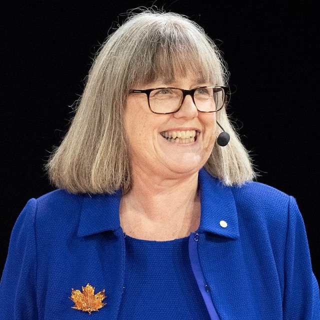 Donna Strickland wearing a head mic whilst giving a talk. She is a white woman with greying hair.