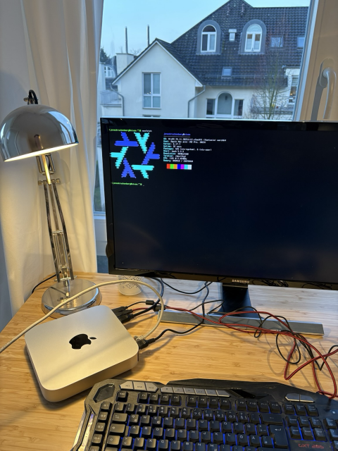 A photo of a macmini, keyboard, mouse and screen showing the nixos neofetch info