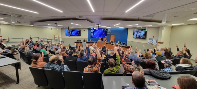 A packed room at Longmont city council chambers, where activists were asked by a speaker to silently raise their hands if they opposed the city renewing the contract with Flock. The entire room raised their hands.
