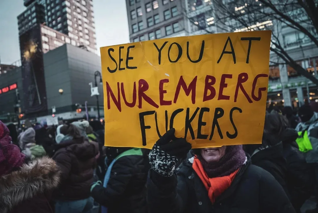 ICE protester holding up a sign that reads "See you at Nuremberg Fuckers."